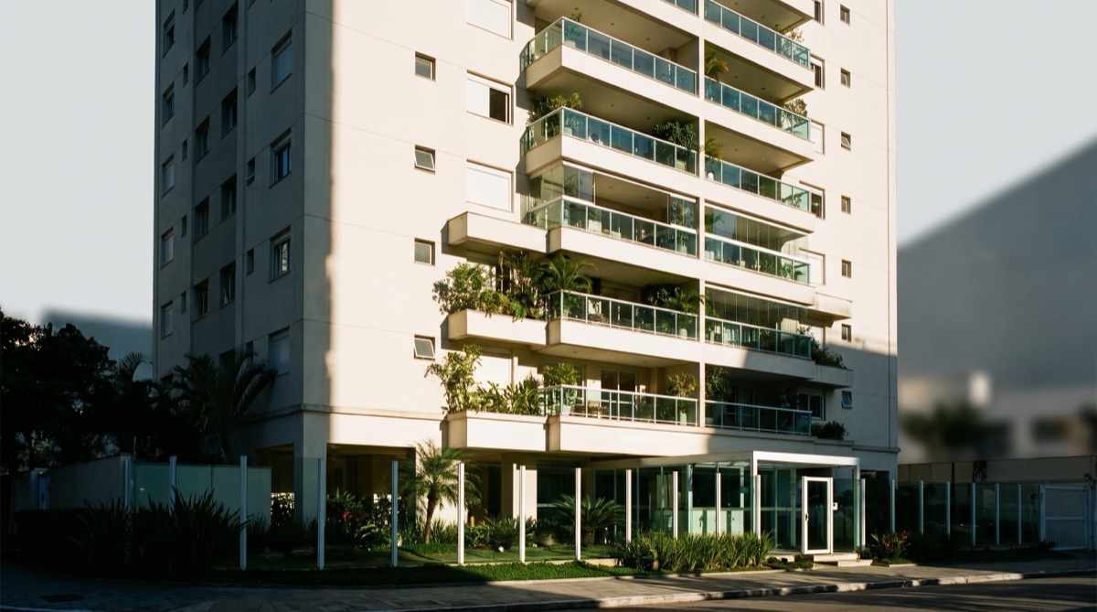 Torre residencial de condomínio com varandas e portaria envidraçada